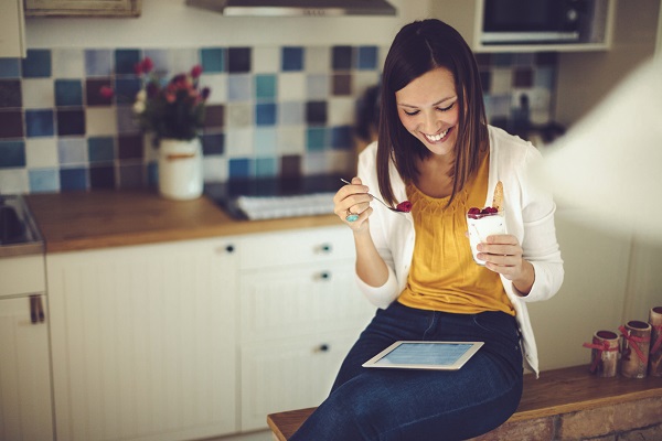 Beautiful young woman having breakfast in the kitchen