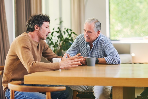 Adult son and father talk over coffee