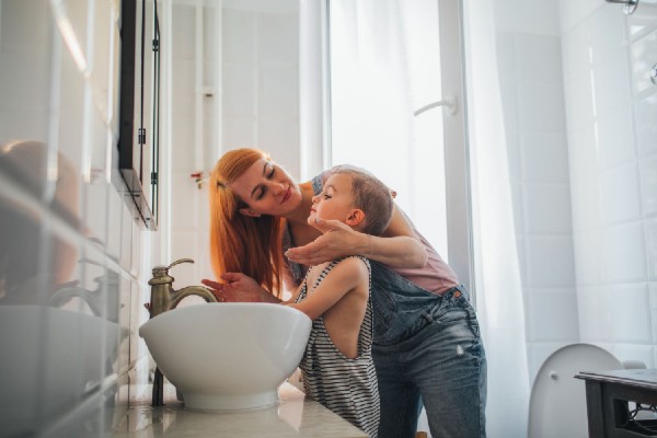 A mum applying face cream on her kid in bathroom